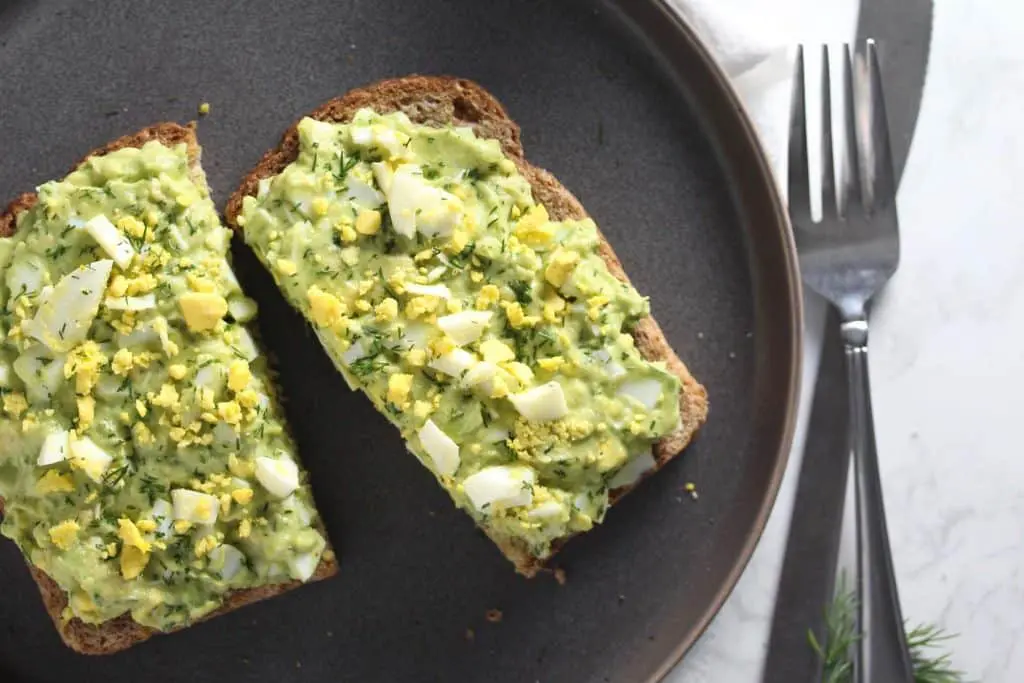 Avocado egg salad toast on grey plate.