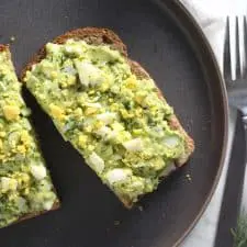 Avocado egg salad toast on grey plate.