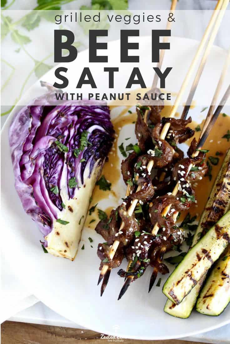 Beef skewers, grilled vegetables and peanut sauce on white plate.
