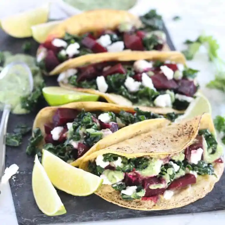 Beet and kale tacos on dark grey serving platter.