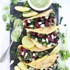 Beet and kale tacos on dark grey serving platter.