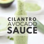 Green sauce in glass bottle on white surface.