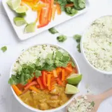 Curry, vegetables and rice in white bowl on marble surface.