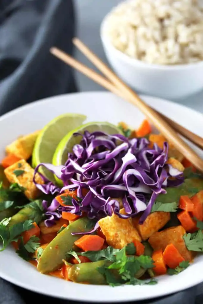 Coconut curry tofu in white bowl on grey surface.