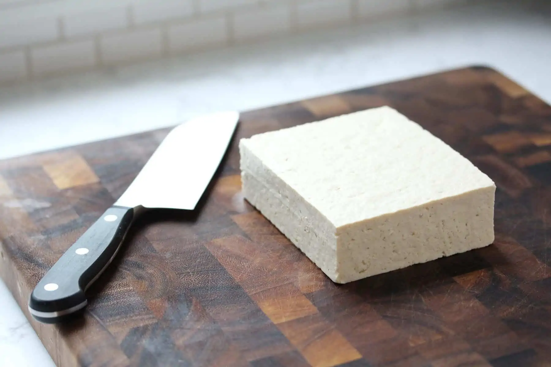 Brick of tofu on cutting board.