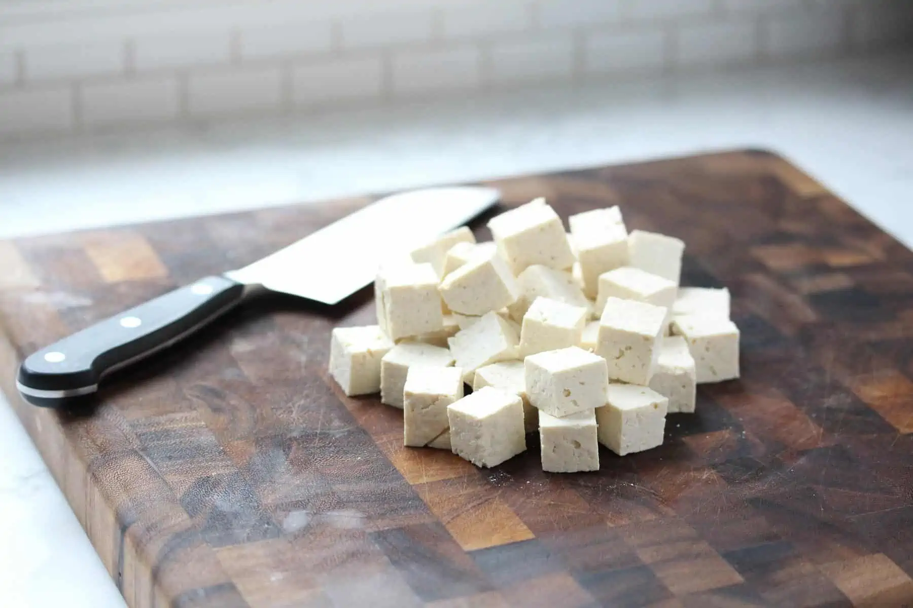Cubed tofu on cutting board.