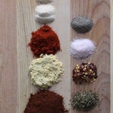 Spices on brown cutting board.
