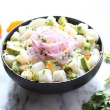 Fish, avocado and red onion in black bowl.