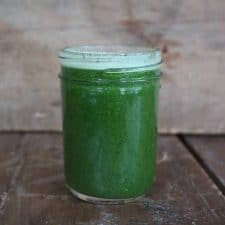 Green juice in mason jar on wood surface.