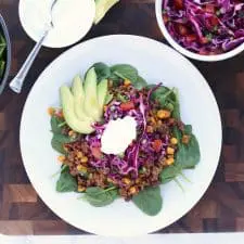 Taco salad on white plate on brown cutting board.