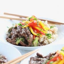 Beef and broccoli stir fry in white bowl with chopsticks.