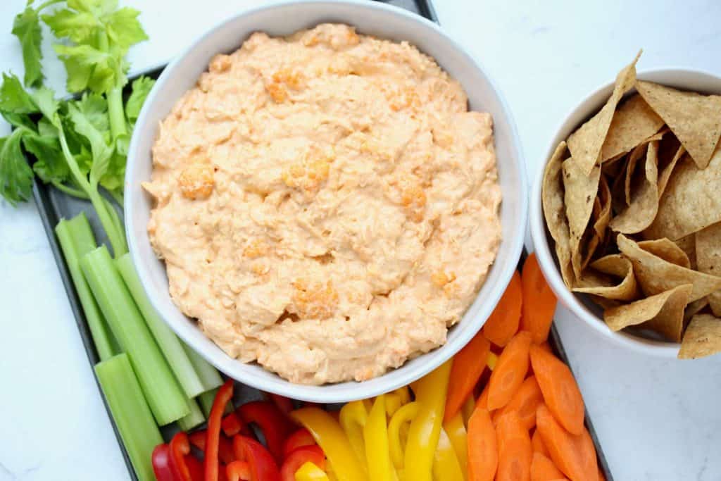 Buffalo dip in white bowl with sliced vegetables.