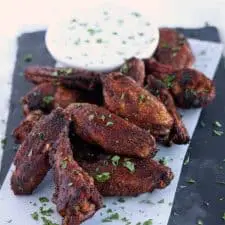 Crispy wings on blue serving platter with dip.