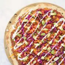 Colorful pizza on white surface.