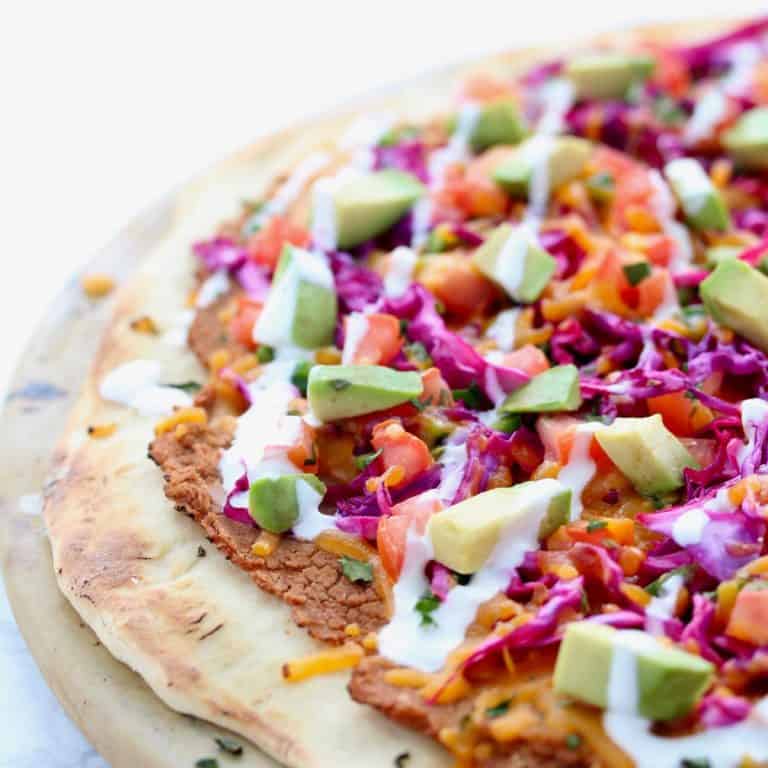 Colorful pizza on white surface.