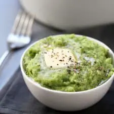 Spinach mashed potatoes in a white bowl on grey napkin.