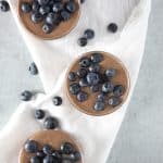 Chocolate pudding in glass on white napkin with blueberries.