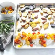 Chicken, tomatoes and baby potatoes on sheet pan.
