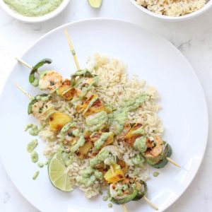 Shrimp skewers and rice on white plate.