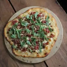 Flatbread on pizza stone on wood surface.