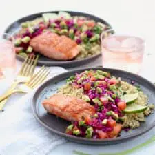 Salmon, quinoa and fresh vegetables on two grey plates.