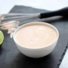 Aioli in white bowl on grey cutting board.