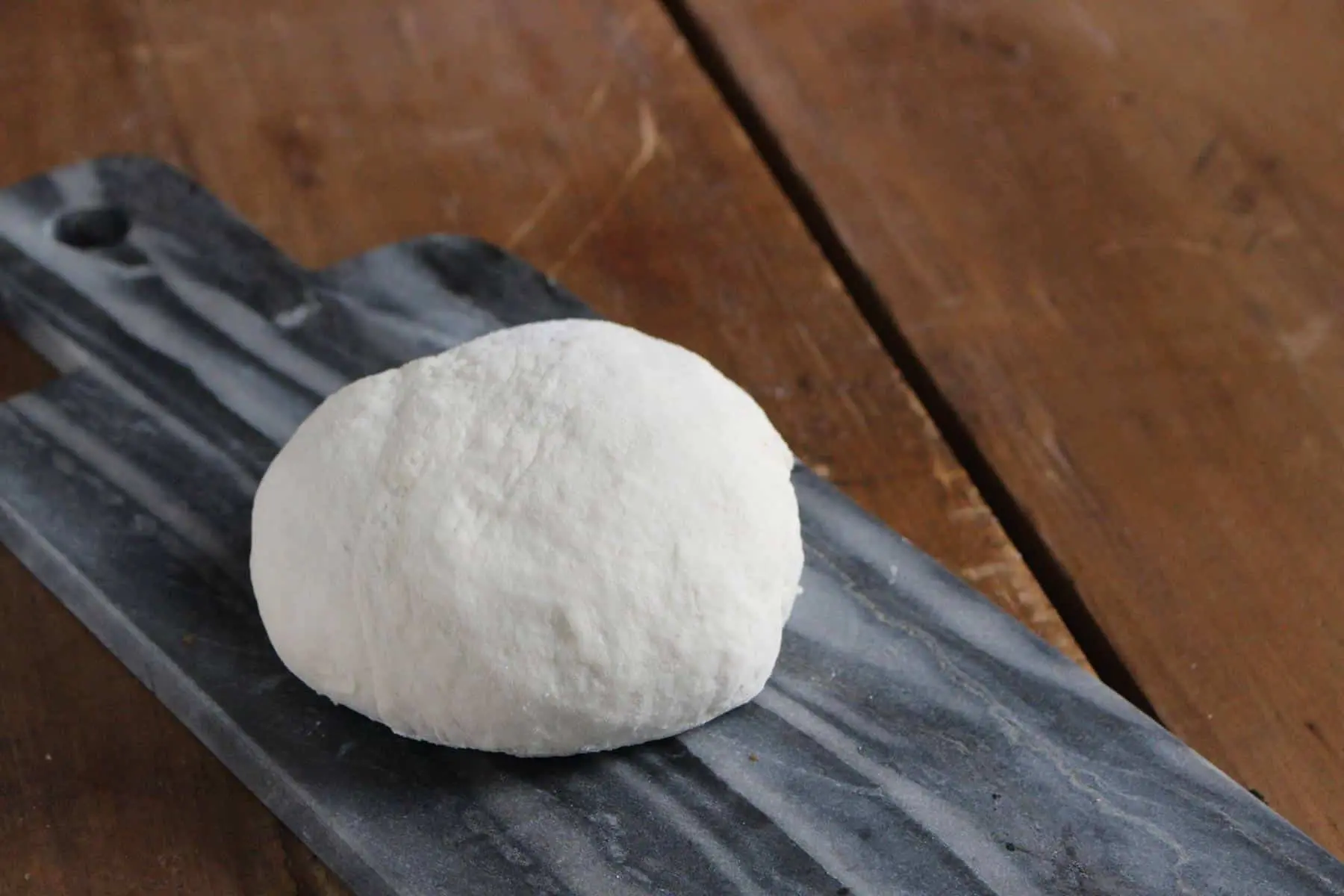 Pizza dough on grey serving platter.